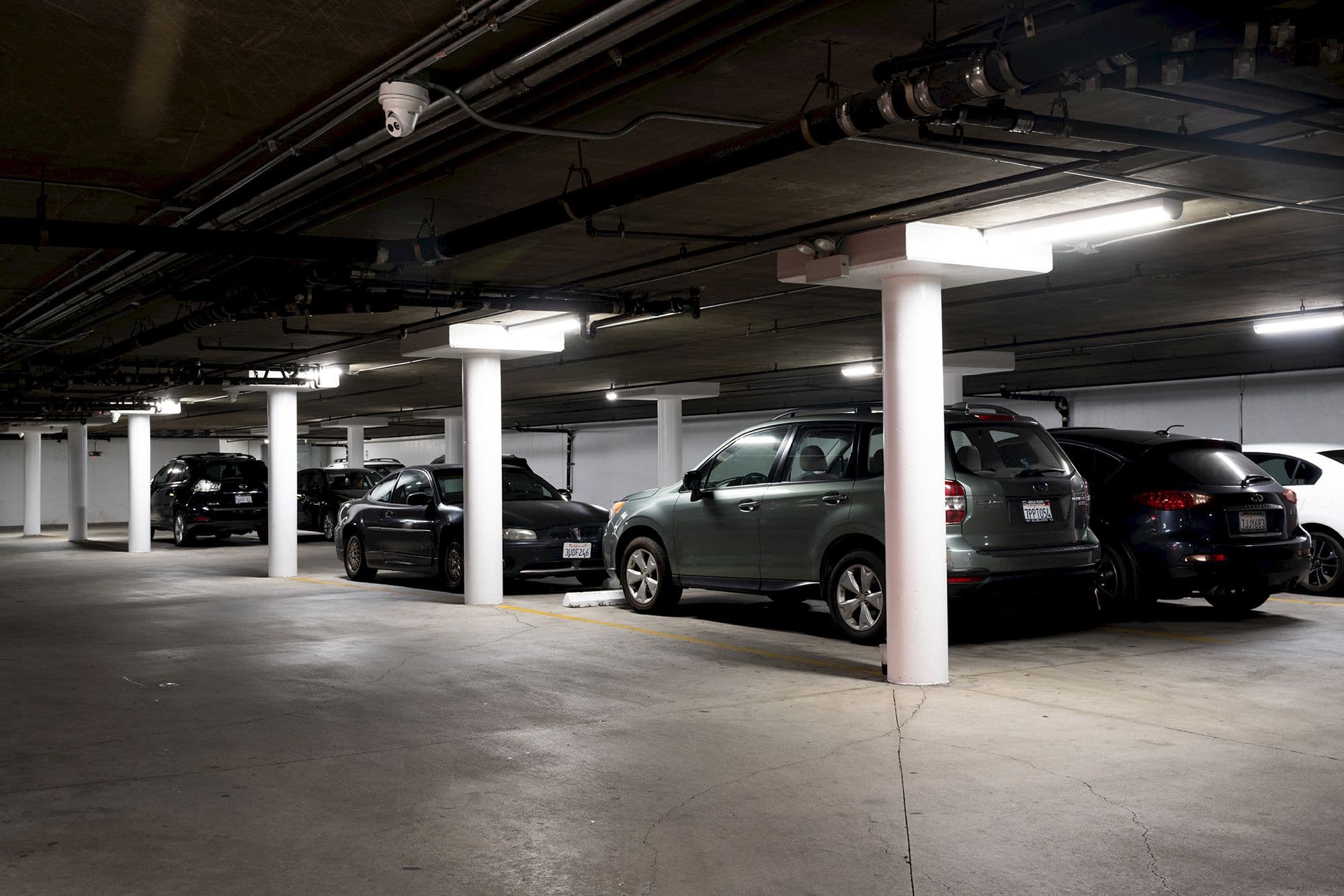 The hotel's covered parking garage with cars parked between white pillars