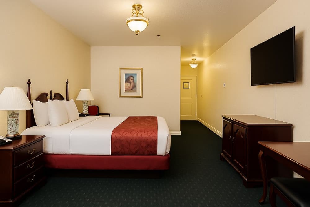 Accessible king room with a wide entry hallway, wall-mounted TV and a cherry wood dresser